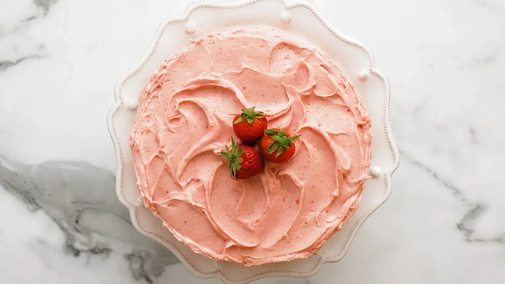 Decorating Strawberry cake after frosting with whole Strawberry