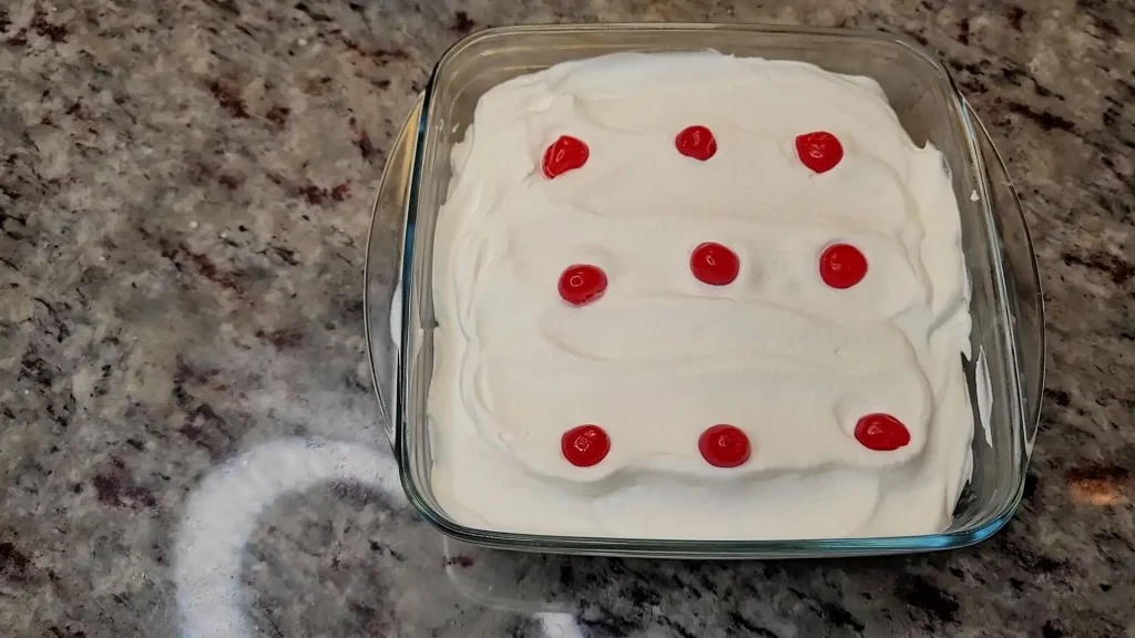 Spreading whipped cream on the cake with fresh fruit